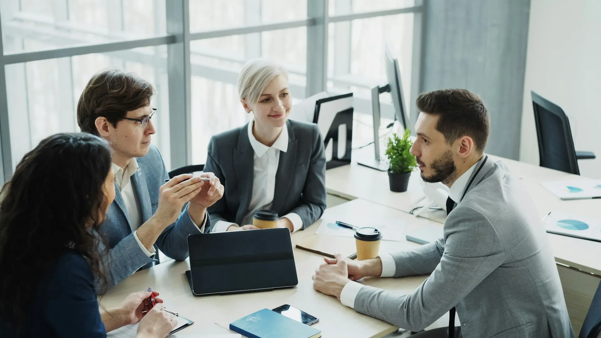 Four colleagues discussing documents around a table in a bright office